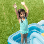 Child playing in inflatable pool outdoors.