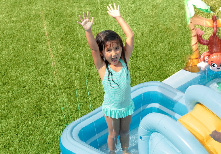 Child playing in inflatable pool outdoors.