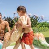 Child in pool with inflatable dinosaur toy.