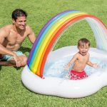 Child splashing in rainbow inflatable pool.