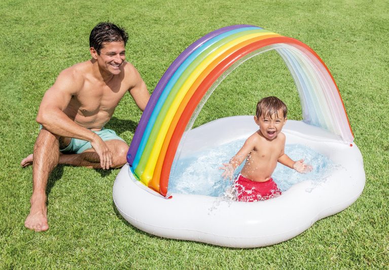 Child splashing in rainbow inflatable pool.