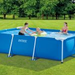Family swimming in blue rectangular pool outside.