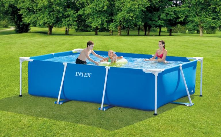 Family swimming in blue rectangular pool outside.