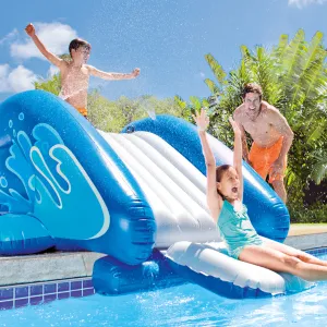 Kids playing on inflatable water slide at pool.