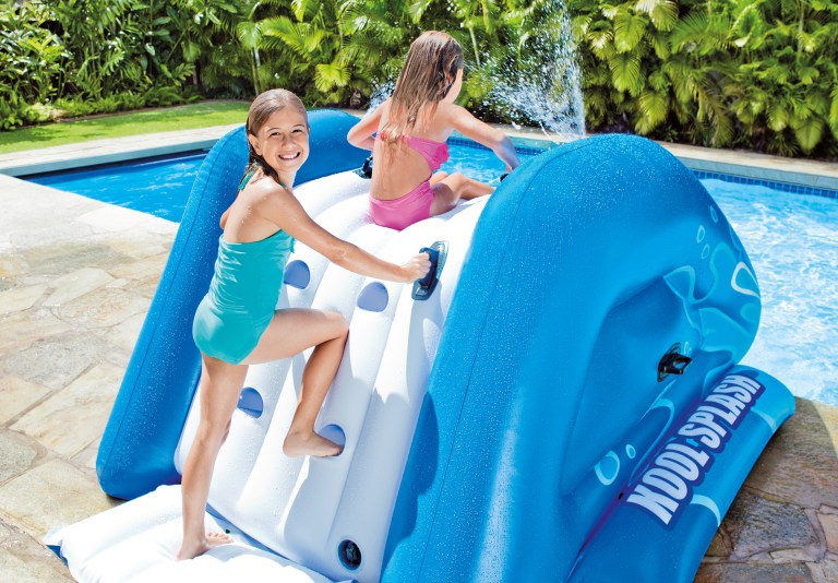 Children play on inflatable water slide in pool.