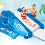 Kids playing on inflatable water slide outdoors.