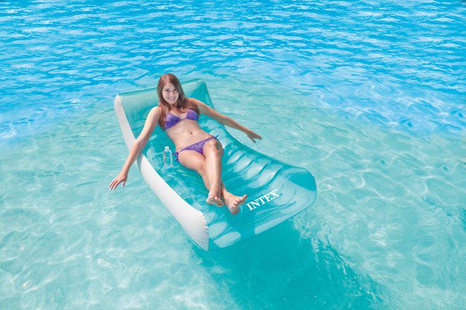 Woman relaxing on float in clear blue water.
