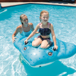 Child and adult on inflatable in pool
