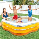 Family having fun in inflatable pool outdoors.