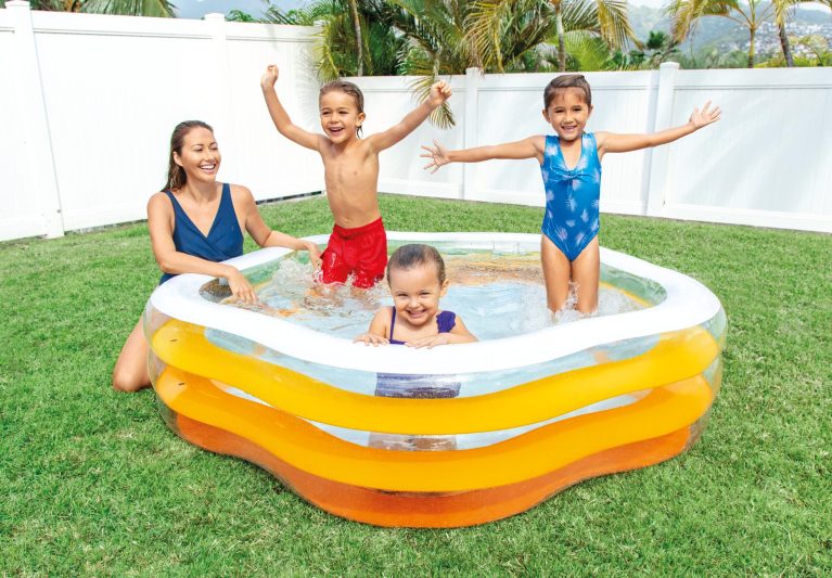 Family having fun in inflatable pool outdoors.