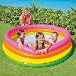 Kids playing in colourful inflatable pool outdoors.
