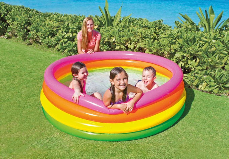 Kids playing in colourful inflatable pool outdoors.