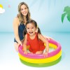 Child and adult in colourful inflatable pool.