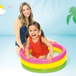 Child and adult in colourful inflatable pool.