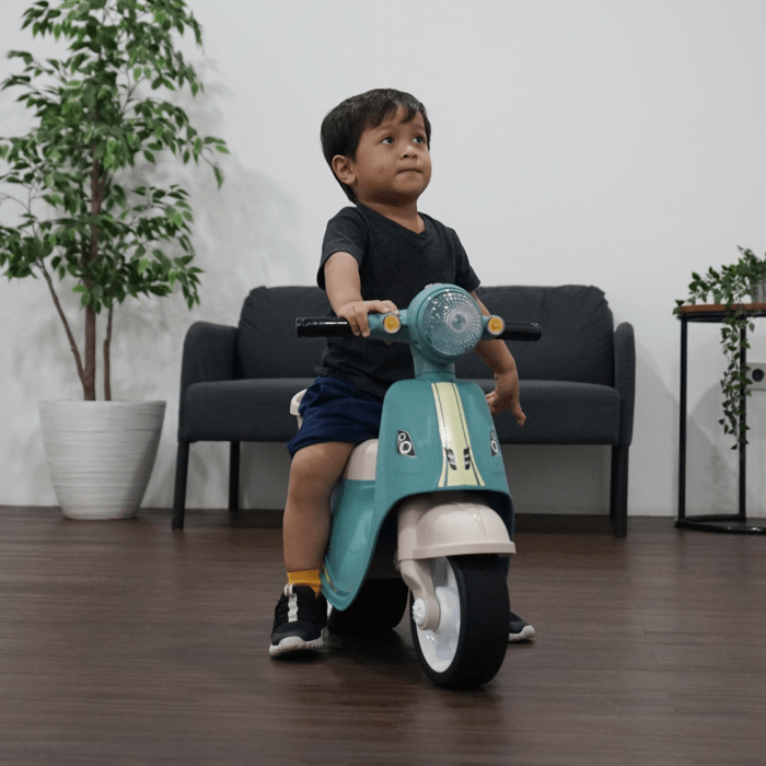 Child riding toy scooter indoors