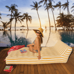 Woman relaxing by tropical pool at sunset.