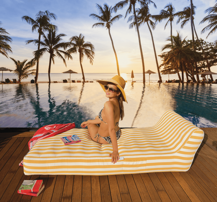 Woman relaxing by tropical pool at sunset.