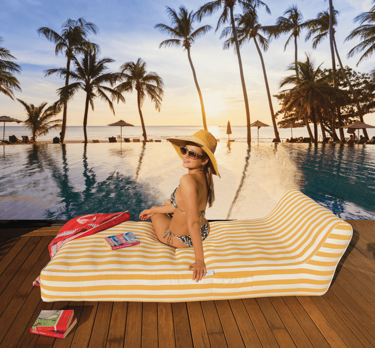 Woman relaxing by tropical pool at sunset.