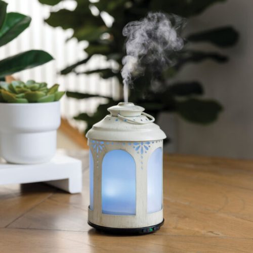 Elegant aroma diffuser releasing mist on wooden table.