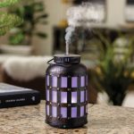 Decorative metal lantern diffuser emitting steam on table.