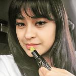 Woman applying green lipstick, close-up view.
