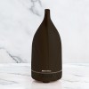 milano decor aroma diffuser 100ml ultrasonic humidifier purifier and 3 pack oils dark wood Dark wood essential oil diffuser on marble surface.