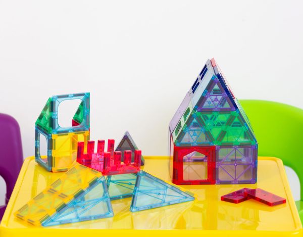 Colourful magnetic tiles forming structures on table.