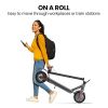 alpha urban 8 electric scooter, suspension, 25km range, 8.5 inch wheels, brushless motor, motorised commuter escooter for adults, grey Person carrying foldable scooter while walking.