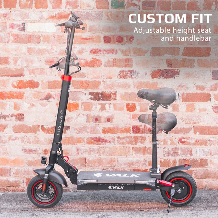 Electric scooter, adjustable seat and handlebar, brick wall background.