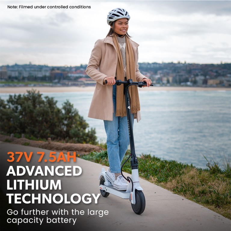 valk 400w electric scooter, with suspension for adults portable folding ride on,synergy 5 mkii white Person riding electric scooter by the water.
