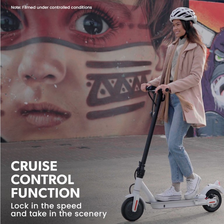 valk 400w electric scooter, with suspension for adults portable folding ride on,synergy 5 mkii white Person rides scooter past street art mural.