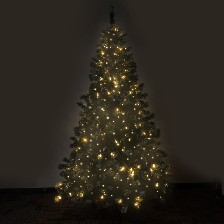 Decorated Christmas tree with glowing lights in darkness.