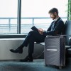 Businessman reading with luggage at airport lounge.