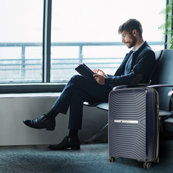 Businessman reading with luggage at airport lounge.
