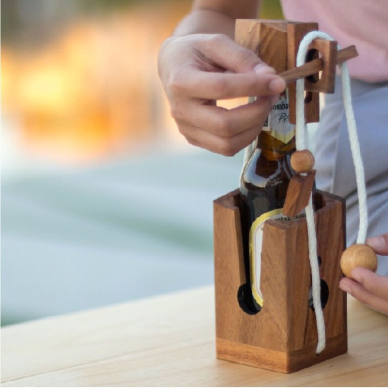 Person solving wooden bottle puzzle outdoors