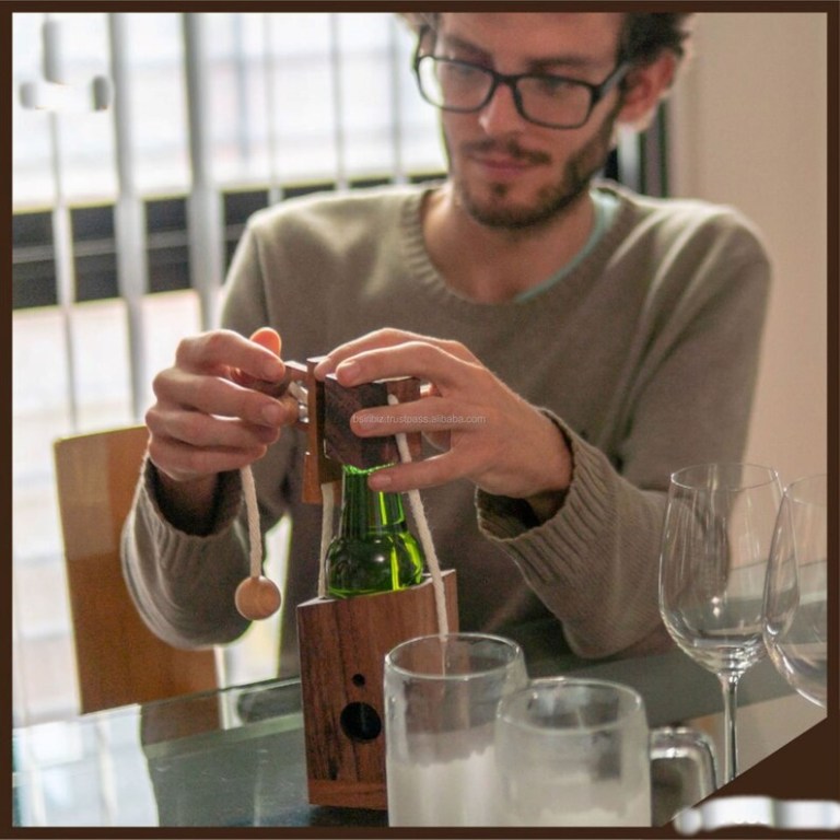 wine stopper lock puzzle party puzzle cant drink it until you crack the lock party fun Man solving wooden bottle puzzle at table.