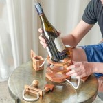 wine stopper lock puzzle party puzzle cant drink it until you crack the lock party fun Person assembling wooden wine bottle holder on table.