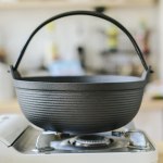 29cm cast iron sukiyaki iron pot japanese shabu shabu pot pan stockpot wooden lid home camping picnic Cast iron pot on gas stove in kitchen.