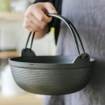 29cm cast iron sukiyaki iron pot japanese shabu shabu pot pan stockpot wooden lid home camping picnic Person holding a cast iron pot with handle.