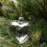 Heart-shaped ornament on pine tree branch.