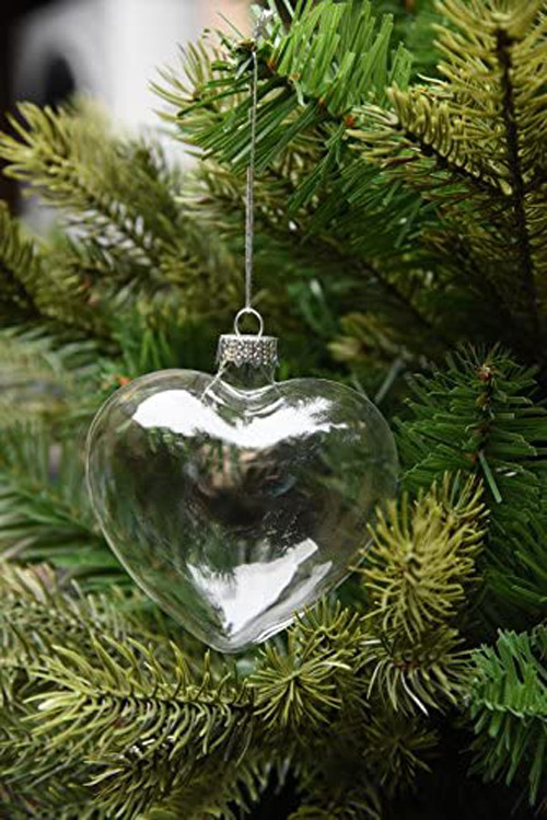 Heart-shaped ornament on pine tree branch.