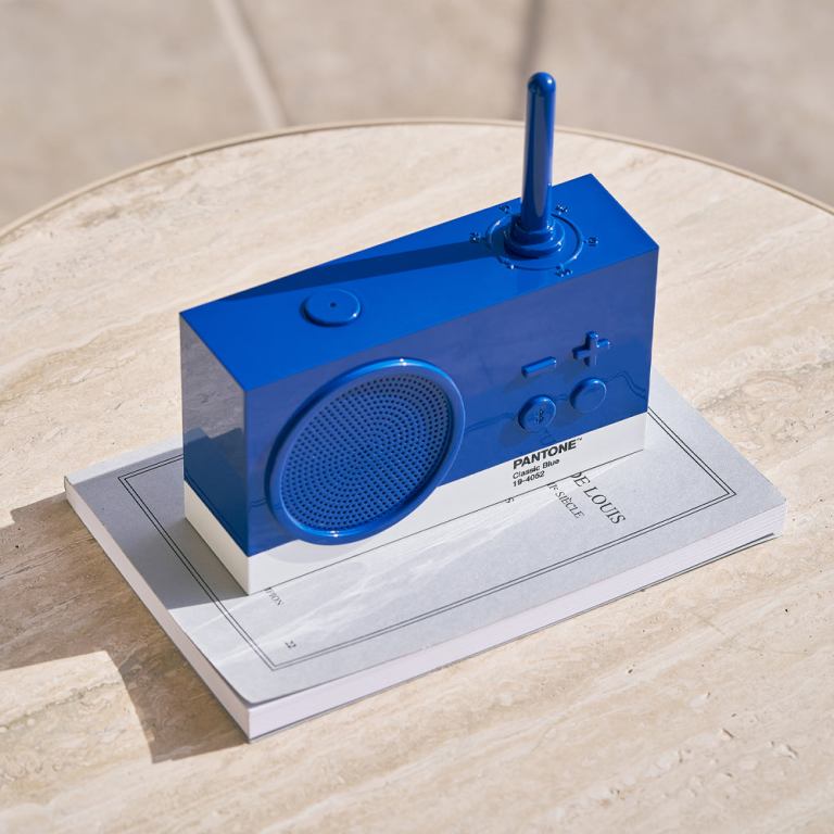 Blue speaker on book on beige table.