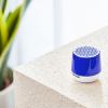 Blue portable speaker on textured white surface.