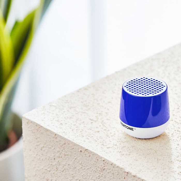 Blue portable speaker on textured white surface.