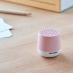 lexon mino+ mini bluetooth speaker pantone rose pink Pink Pantone speaker on wooden desk.