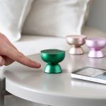 lexon tamo infinitely pairable bluetooth speaker green Hand approaching colourful mini wireless speakers on table.