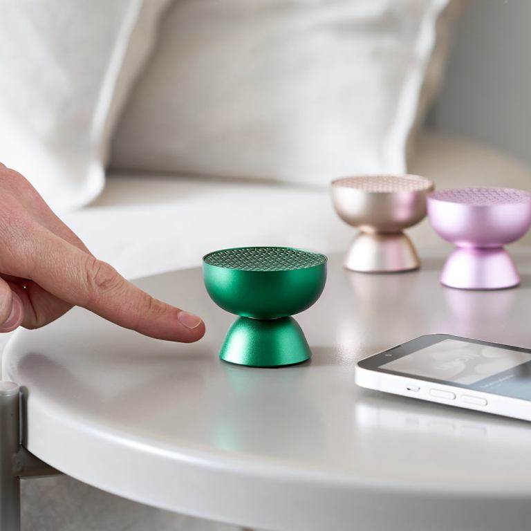 lexon tamo infinitely pairable bluetooth speaker green Hand approaching colourful mini wireless speakers on table.