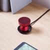Red portable speaker on wooden desk.