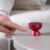 Finger pointing at small red speaker on table.