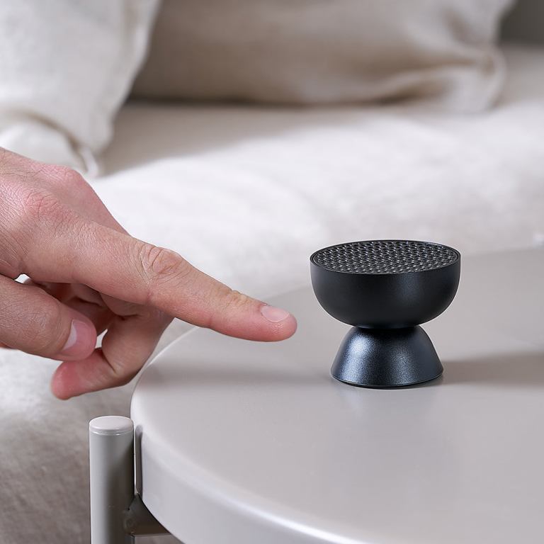lexon tamo infinitely pairable bluetooth speaker black Finger pointing at small black speaker on table.